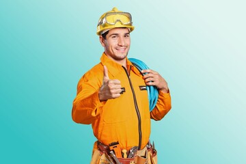 Young electrician man carrying cables posing on background