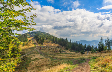 Fototapeta na wymiar View from the Klimczok peak in the Silesian Beskids (Poland) on the Siodło pass and the Magura peak (the PTTK Klimczok mountain shelter is visible below the peak) on a sunny autumn day.