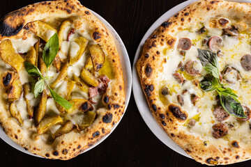 Due pizze tradizionali napoletane con mozzarella, salsiccia, patate al forno e basilico fresco fotografate dall'alto