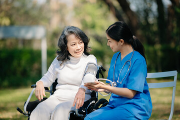 Fototapeta na wymiar Elderly asian senior woman on wheelchair with Asian careful caregiver. Nursing home hospital garden