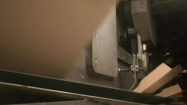 Machine tool folds and transport cardboard boxes in plant workshop closeup. Carton packaging production technology at factory