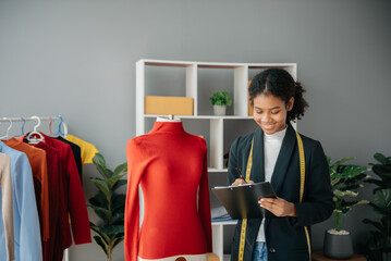 Diverse female fashion designers at work with tailor centimeters on necks and holds tablet and smartphone. independent creative design business. .