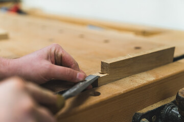 Carpenter uses a chisel to smooth out wooden plank wipes out crumbs from surface. High quality photo