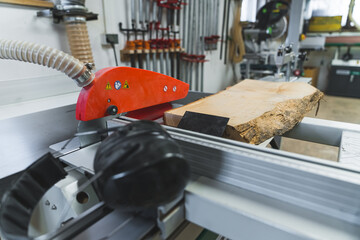 Carpenter using electrical table saw to cut wooden plank in a woodworking studio. High quality photo