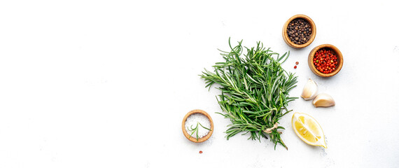 Fresh rosemary, sea salt, black and pink pepper, garlic and olive oil on white kitchen table background. Spices and herbs for cooking. Top view, copy space banner