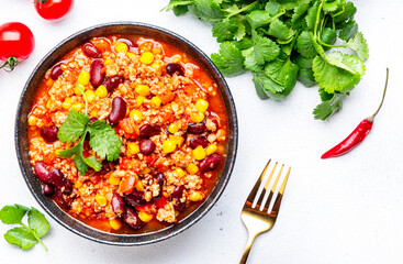 Chili con carne with minced beef, red beans, paprika, sweet corn and hot peppers in spicy tomato sauce, tex-mex cuisine dish, white table background, top view