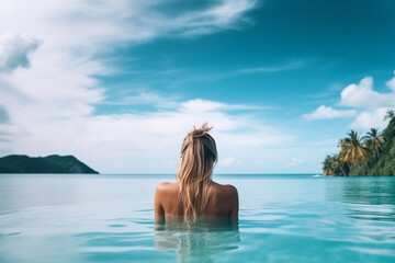back view of Young caucasian woman in swimming pool on beautiful tropical bay blue sky and ocean summer vacation concept