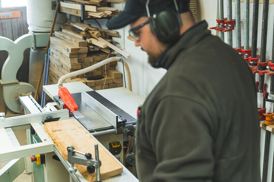 Carpenter fixing a wooden plank using clamp to cut it with a circular table saw. High quality photo