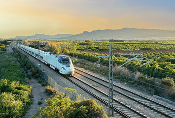 Train on railway on sunset in mountain. Speed train in motion on Valencia railroad. European...
