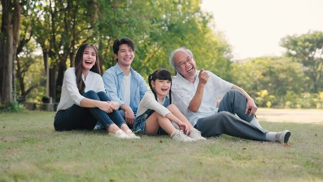 Asian family talking and sitting on grass in a park during summer morning, Relax time