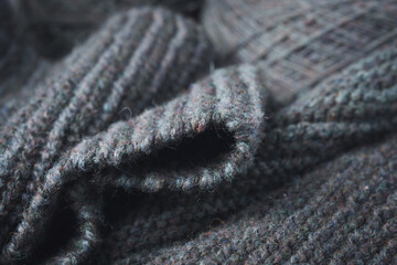 Fototapeta na wymiar Knitted scarf folds, black and gray stripes. Dark knitted texture background.