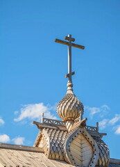 Wooden carved dome of the Orthodox Church with a cross on the sky background