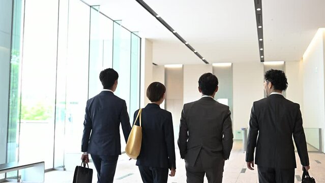 会社のロビーやエントランスで背景にスーツを着て颯爽と歩くカッコいい日本人(アジア人）ビジネスマンチームの動画　全身　コピースペースあり	