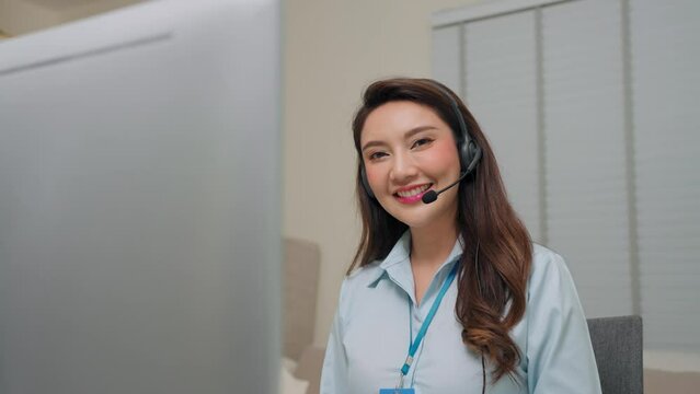 Young Asian woman call center with headsets talking with customer in sales room at office and looking at camera, Telemarketing sales or Customer service operators concept