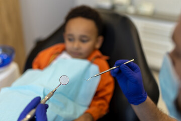 Dark-skinned cute boy looking frightened while sitting at the dentists office