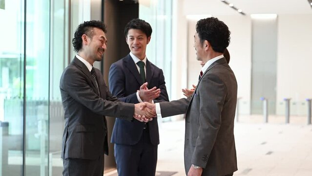 Successful business image of backlighting, shaking hands, contract signing, cooperation, etc. photo of cool Asian man in suit.