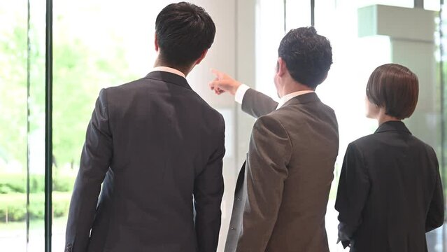 スーツを着て歩くカッコいい日本人(アジア人）ビジネスマンチーム上半身の後ろ姿の動画　目標を指さす　コピースペースあり