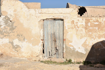 Rough Outdoor Stucco Wall with Dilapidated Light Blue Wood Door in Takrouna, Tunisia