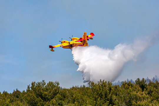 Incendie - Avion larguant de l'eau sur un feu de forêt dans un massif boisé montagneux