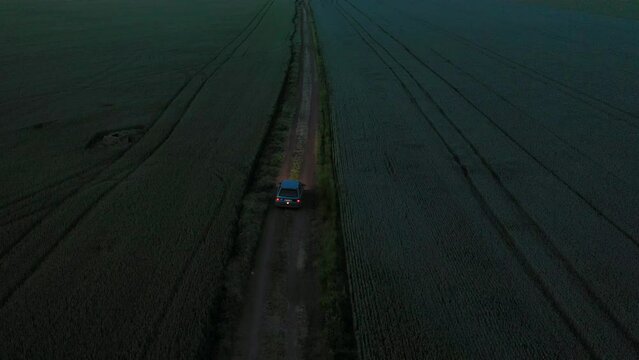 Aerial view to a car in a field of wheat at night
