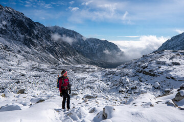 Hiker woman standing and looks around, admiring winter mountain landscape. Happy tourist woman in...