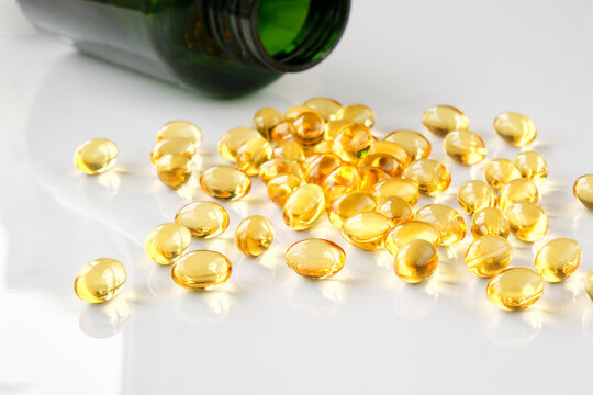 Close-up of many omega-3 oil capsules on a white table