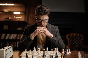 Focus on serious young man looking thoughtfully at chessboard pieces