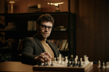 Portrait of man chess player in waiting position at table with chessboard