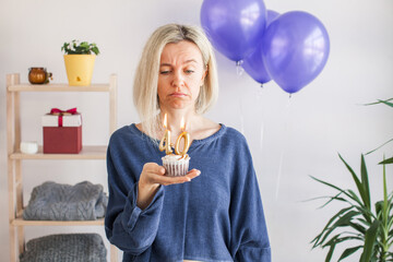Adult unhappy beautiful woman forty years with festive cupcake with candle