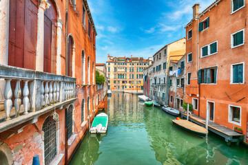Fototapeta na wymiar Fabulous cityscape of Venice with narrow canals, boats and gondolas and bridges with traditional buildings