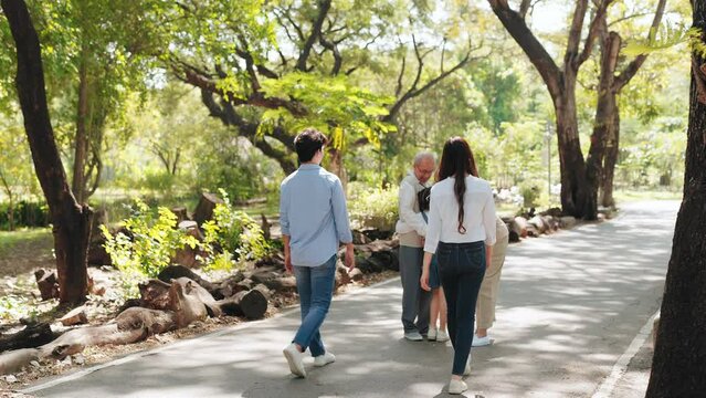 Happy Asian family come to visit grandparents smiling and entwining in the nature park, Big family standing and entwining in the public garden concept