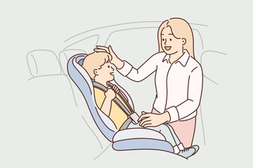 Mother puts son in car seat to ensure safety of child during transportation to kindergarten