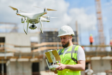 Drone operated by safety engineering inspector. Construction worker piloting drone on building site - 605247134