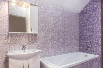 Laconic design of the bathroom decorated with mosaic tiles. A cabinet with a mirror over the sink,...