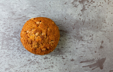 Top view of a delicious freshly baked cinnamon muffin on a gray mottled tabletop.