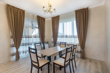 The  interior of the dining room in a luxurious country house. Windows with beautiful curtains, elegant furniture.