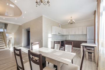 Kitchen with a laconic interior design in pastel colors. Stylish furniture. Open floor plan, stairs to the second floor.