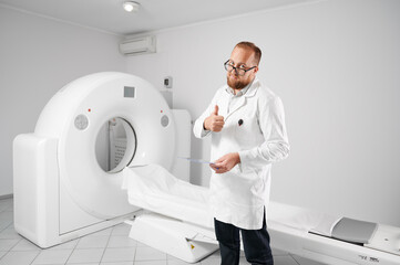 Portrait of doctor with medical computed tomography or MRI scanner. Radiologist holding results of...