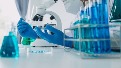 biochemical research scientist team working with microscope for coronavirus vaccine development in pharmaceutical research labolatory, selective focus