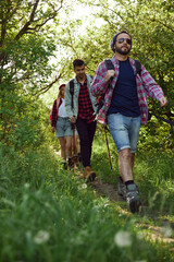 Active leisure time with friends. Young people, men and women in casual clothes walking in forest on warm spring day. Concept of active lifestyle, nature, sport and hobby, friendship