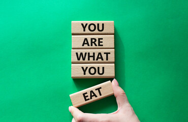 You are what you Eat symbol. Concept words You are what you Eat on wooden blocks. Beautiful green background. Doctor hand. Healthy eating and You are what you Eat concept. Copy space.