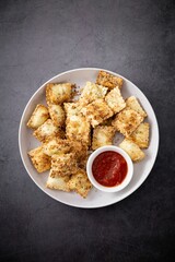White bowl filled with toasted ravioli and a savory dipping sauce