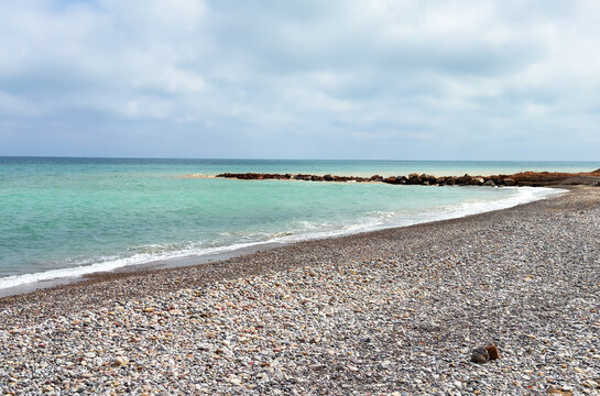 Pebble stone beach in Nules, Castello. Sea beach shore. Waves in sea near coastline on empty pebble beach. Sea beach landscape. Coast pebbles. Shore landscape on Spain resort. Ocean shoreline scenic.