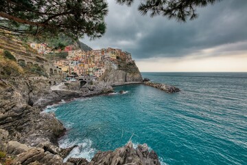Scenic vista of tranquil blue water with small houses on a shoreline ciff in Manarola, Cinque Terre