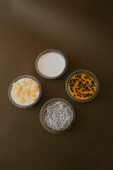 Vertical shot of plastic bowls of various creamy pudding on a brown surface