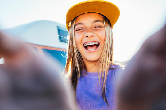 Beautiful teen girl taking selfies in a yellow cap and bracket on her teeth.