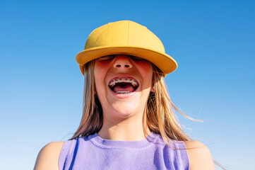 Happy teen girl taking selfies in a yellow cap and bracket on her teeth.