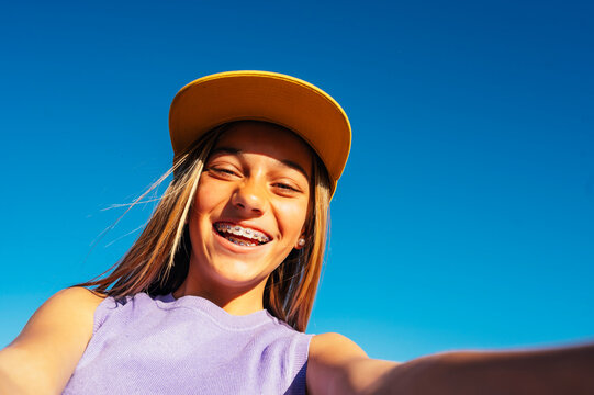 Beautiful teen girl taking selfies in a yellow cap and bracket on her teeth.