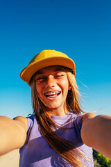 Beautiful teen girl taking selfies in a yellow cap and bracket on her teeth.