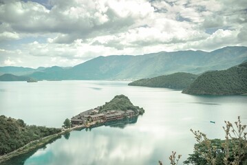 Beautiful view of a peninsula in Lugu lake under a blue sky with clouds in China.